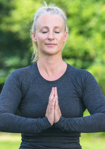 An adult woman with blonde hair practicing meditation