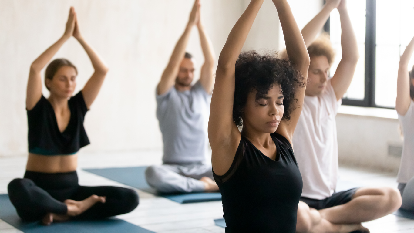 African trainer and group of people meditating during yoga class