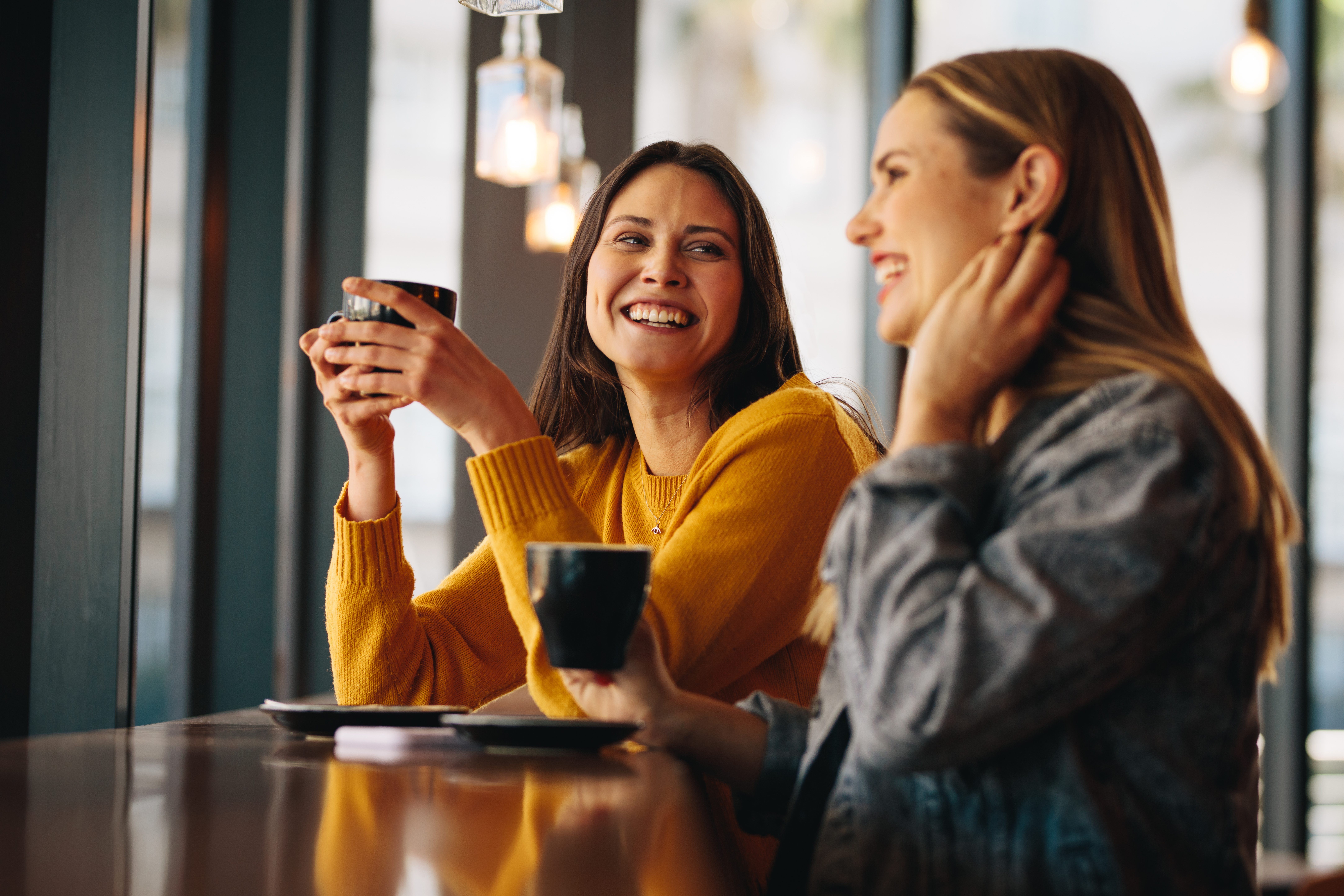 two-female-friends-sitting-at-cafe-having-coffee-and-gossiping-female-friends-meeting-in-a-coffee-shop-on-a-weekend-stockpack-istock Two female friends sitting at cafe having coffee and gossiping. Female friends meeting in a coffee shop on a weekend.