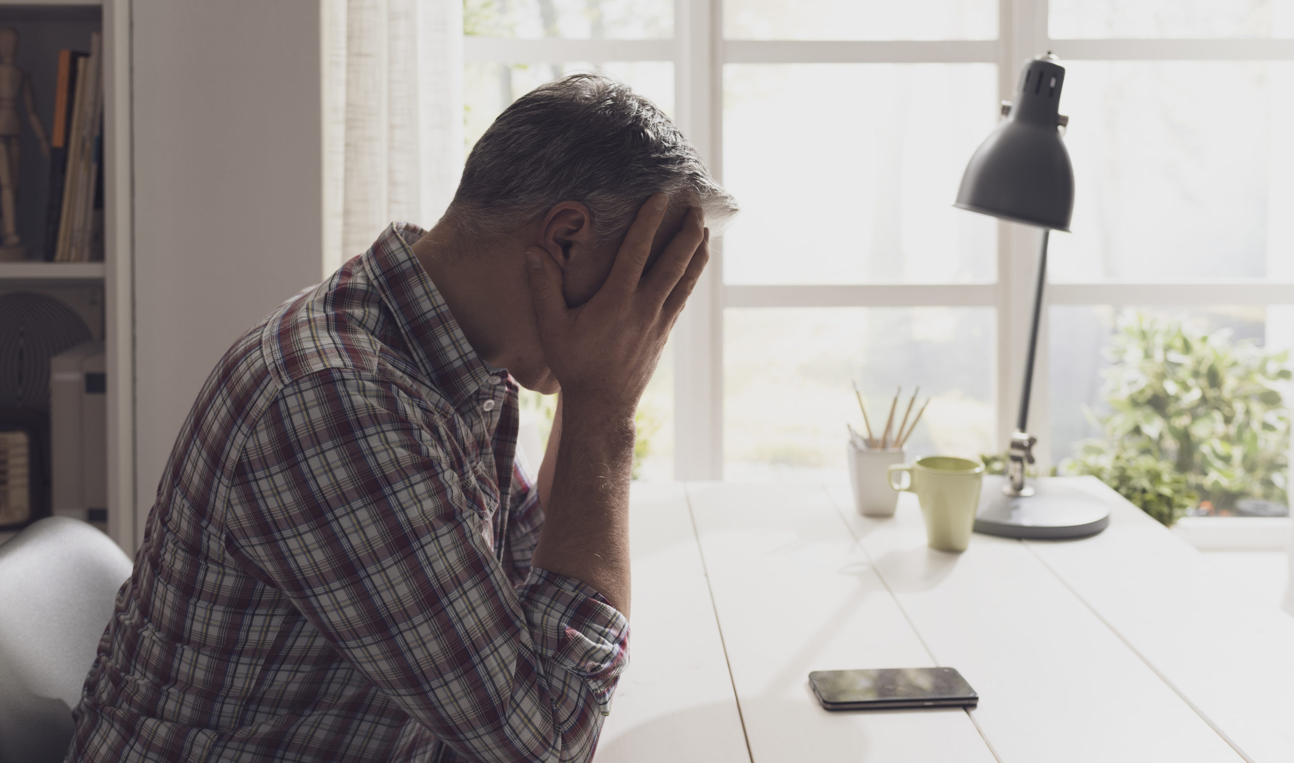 desperate-man-waiting-for-a-phone-call-at-home-he-is-staring-at-the-phone-with-head-in-hands-stockpack-istock