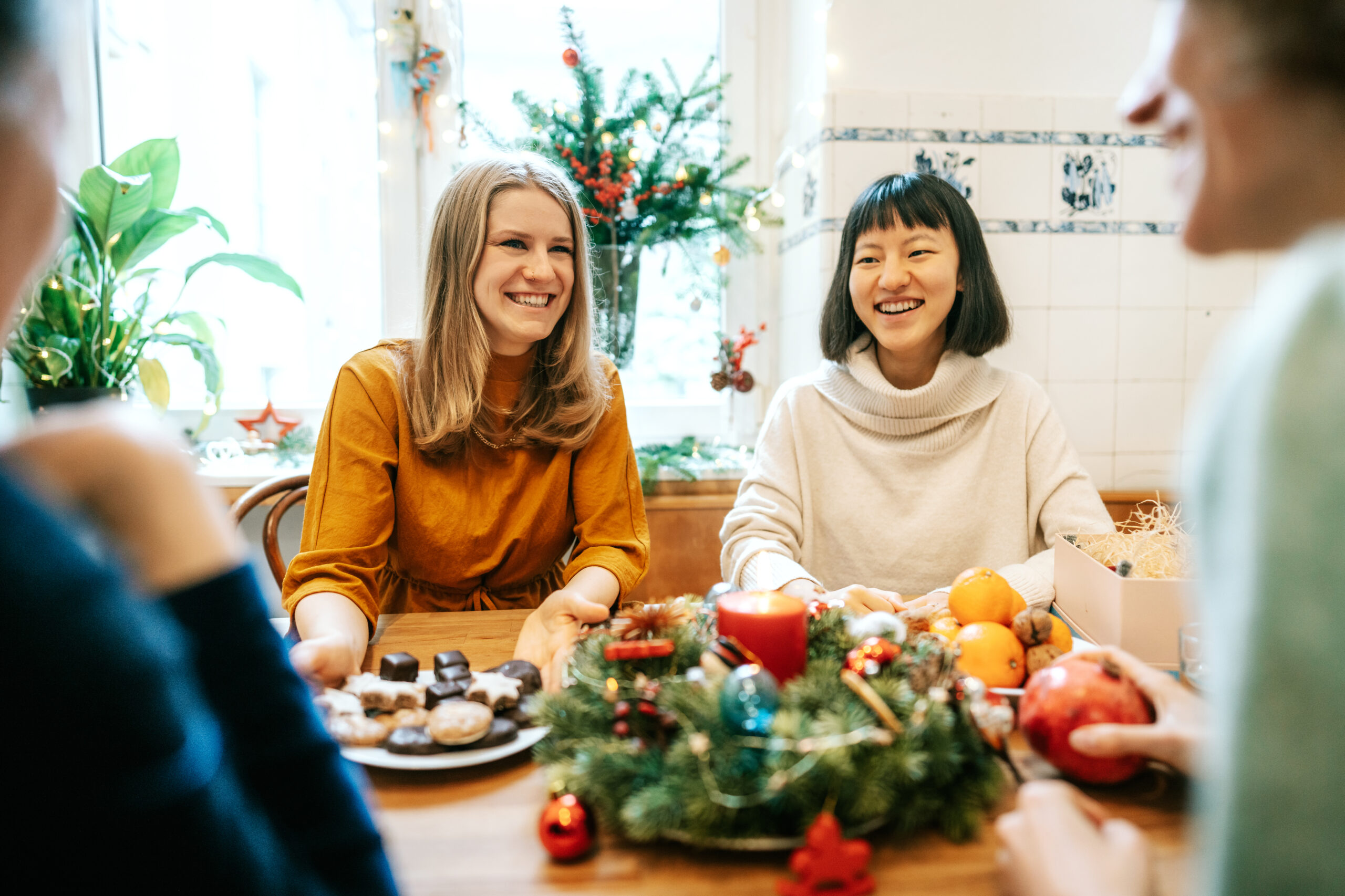 Group of women having food while sitting at festive table during Christmas. Multi-ethnic group of female having Christmas meal together at home.
