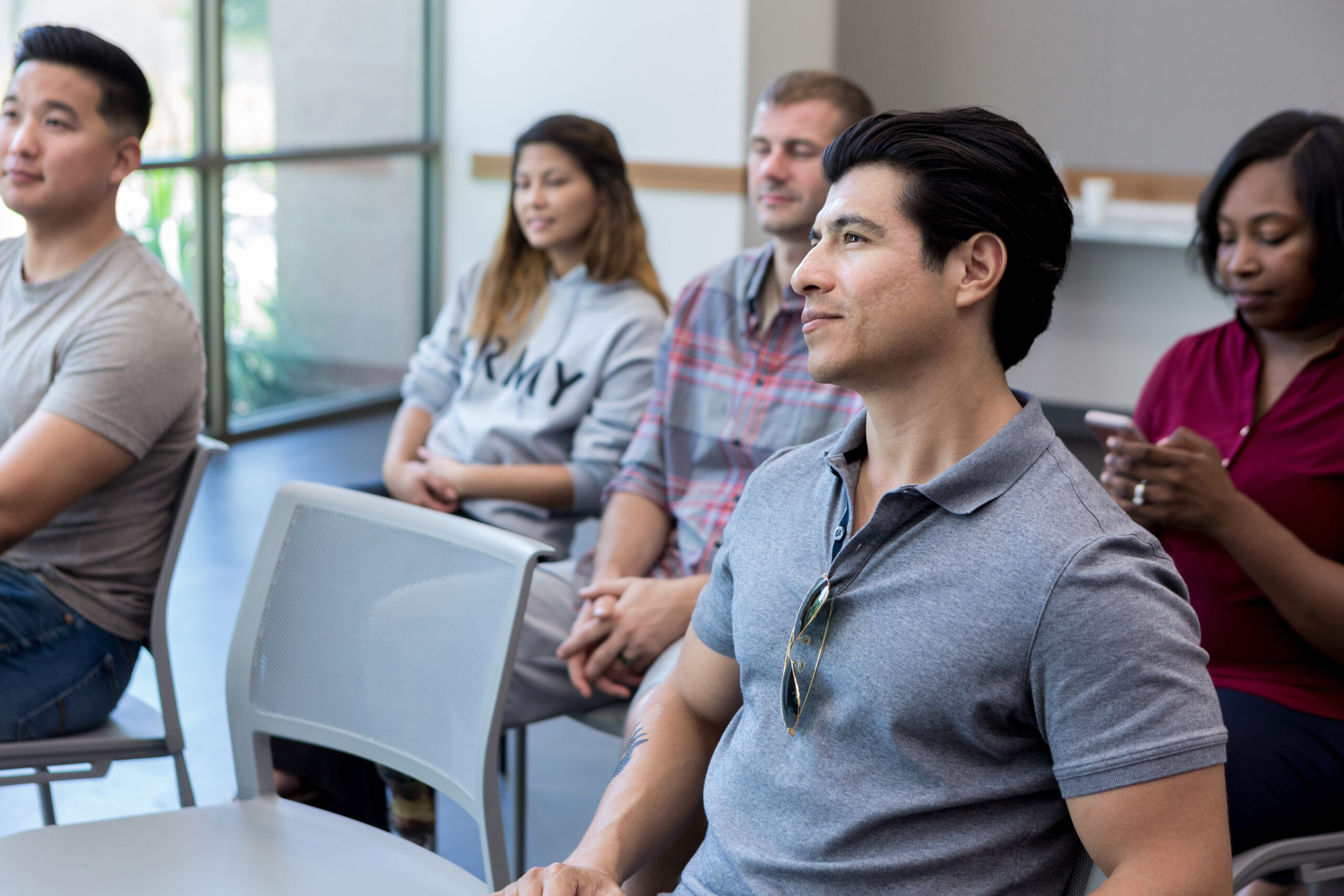 An audience of military veterans attend a seminar for veterans. They are listening attentively to the speaker.