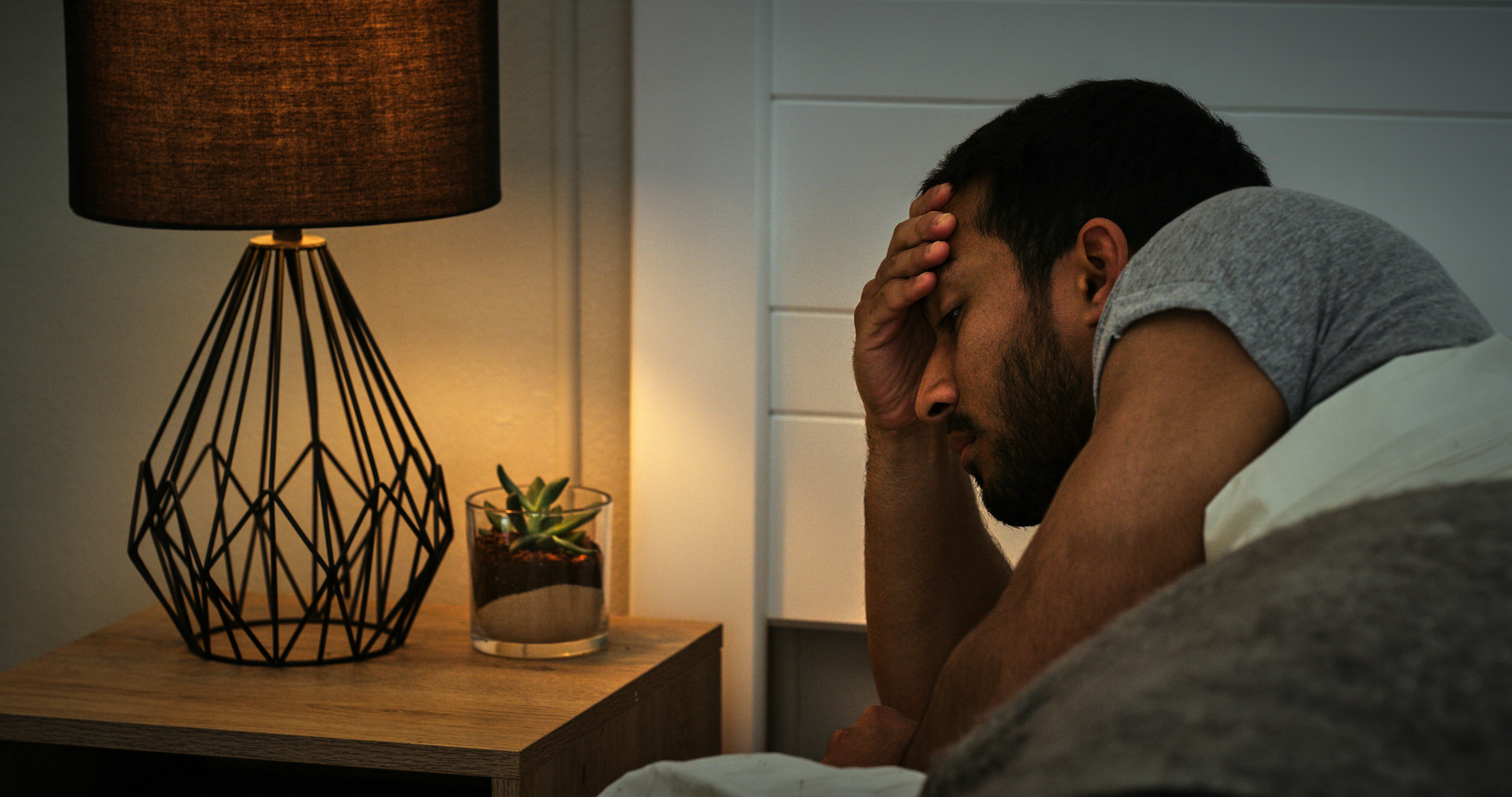 Man, stress and anxiety in bed in the morning with depression, insomnia or mental health in bedroom. Person, sleep apnea or thinking with problem, mistake or worried or sleepless in apartment or home
